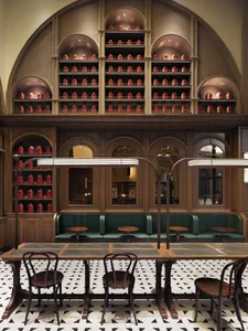 A modern restaurant bar with wooden tables, metal railings, and glass displays.