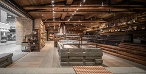 工業風餐廳室內視圖，展示裸露磚牆、木樑與石材點綴。