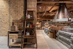 A modern bakery interior with a rustic wood theme featuring shelves, baskets, and a bread oven.