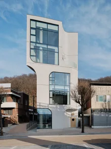 A minimalist, modern building with large glass windows and concrete walls.
