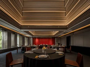 Modern restaurant interior with black tables, red backdrop, and muted color scheme.