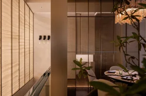 Interior of a minimalist restaurant featuring glass walls and a modern dining setup.