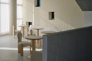 Minimalist, modern cafeteria with concrete walls, round tables, and contemporary seating.