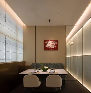 A modern private dining room with a neutral color palette, featuring a table set for four, white chairs, and a red abstract p