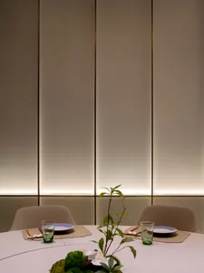 A well-dressed table setting in a modern restaurant, featuring minimalist design elements and a green plant centerpiece.