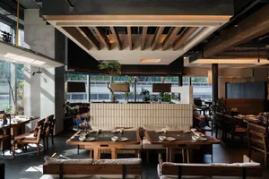 Contemporary restaurant interior featuring wooden tables and concrete walls.