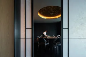 現代餐廳室內，黑色金屬餐桌搭配周圍座椅，以及圓形燈具