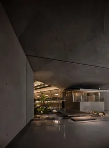 An industrial-style interior design featuring concrete walls and a courtyard with plants and stones.
