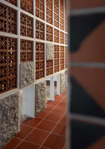 Modern interior design featuring brick facade with intricate wall pattern and terracotta flooring.