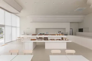 A minimalist coffee shop with tables and chairs, a counter displaying pastries, and a sleek, white interior design.