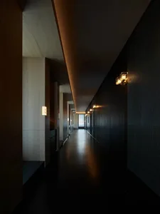 A modern minimalist corridor with floating lights and dark interior walls.