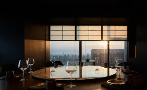 Modern restaurant interior with glass walls and sunset view.