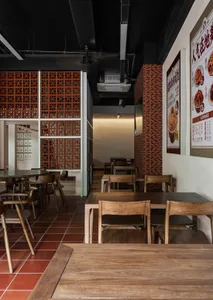 Interior view of a cafe with brick and wooden elements, featuring tables and chairs with a menu on the wall.
