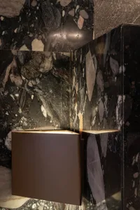A modern interior space featuring marble walls with illuminated lighting fixtures.