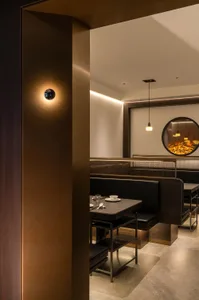 A modern restaurant interior with concrete walls and wooden booths.