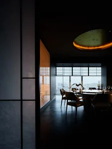 Modern restaurant interior with dark wood flooring and large windows overlooking a cityscape.