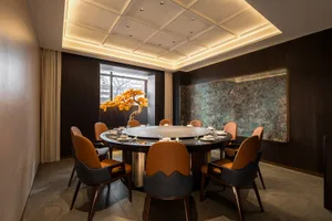 A modern interior design featuring contemporary furniture, a round dining table, and a decorative tree centerpiece.