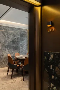 Modern restaurant interior with marble walls, concrete floor, and leather chairs.