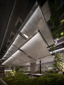 Industrial-style greenhouse with a steel roof, concrete walls, and plants.