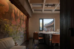 Modern, minimalist restaurant interior with concrete walls and a view through a window