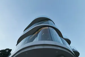 Modern architectural design featuring curved glass frontal exterior surfaces of a tall skyscraper.