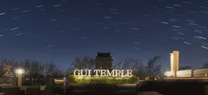 Night sky with stars and a temple sign in the foreground, illuminated by outdoor lights.