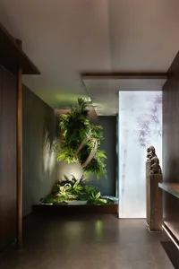 Lobby featuring minimalist design with greenery, wood, and concrete elements.
