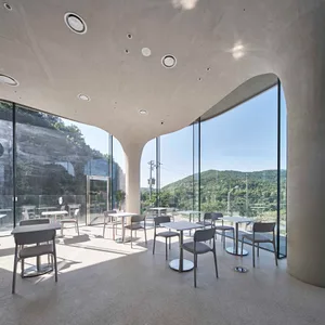 A modern cafe interior featuring glass and concrete materials, with seating and tables designed for functionality and aesthet
