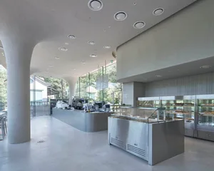 A modern coffee shop interior with a concrete floor and walls, featuring a counter and display cases.