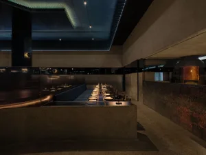 Long, sleek table in a dimly lit, modern restaurant interior made of concrete