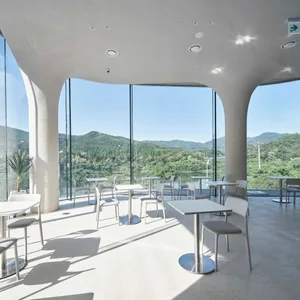 Modern restaurant interior with concrete and glass materials, featuring a minimalist design and open seating area.