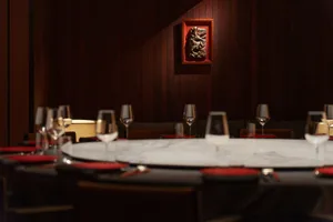 Modern restaurant dining room featuring marble countertops and wooden seating.