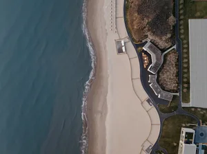 An aerial view of a beachfront architecture with sandy beach and ocean waves.