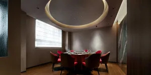 Modern dining room with concrete walls, red accent walls, and a round dining table.