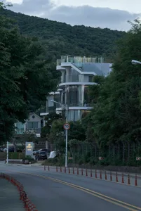 A modern house exterior with glass walls and concrete structural elements.