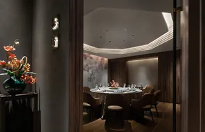A modern restaurant dining room with dark wood accents and a round table set for a meal.