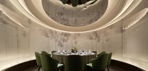 Elegant, modern restaurant interior with paper wall covering, carpet, and green chairs.