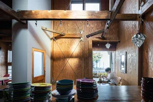 A modern restaurant interior featuring wooden materials and hanging lights.