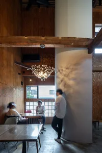 An industrial-style coffee shop interior with wooden walls and a modern chandelier.