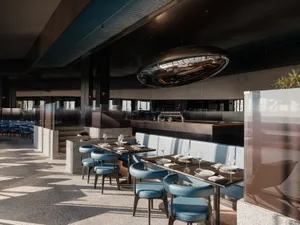 A modern, minimalist restaurant interior featuring metal, concrete, and leather materials.