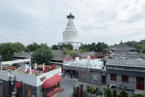 Urban street view featuring a white stone pagoda with a traditional tiled roof.