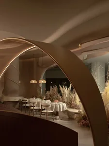 A modern restaurant interior with minimalist design, featuring white walls, wooden elements, and natural light.