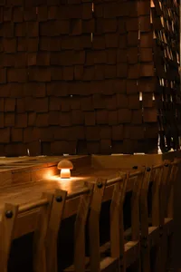 A modern restaurant with wooden furniture and lighting creating a cozy atmosphere.