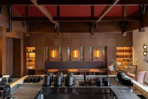 Industrial-style restaurant interior with wooden walls and seating, illuminated by warm lighting.