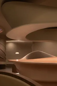 A modern interior space featuring a wooden sculpture with smooth, organic shapes.