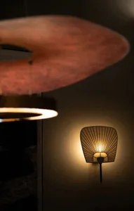 Modern lighting fixture with a shell-like design, featuring a metal base and glass shade emitting a warm glow.