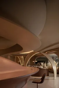 A modern restaurant interior with curved concrete structures and ambient lighting.