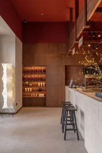 現代餐廳室內設有木質層架展示罐子與杯子，吧台配有高腳椅，以及一盞白色紙燈籠