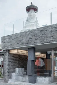 Modern storefront with brick and marble elements, featuring a glass wall and outdoor seating.