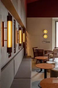 Modern restaurant interior featuring wooden seating and table arrangements with decorative lighting fixtures.